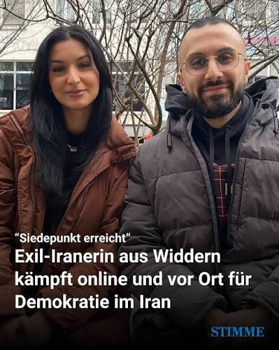 Zwei iranische Aktivisten mit Zeitungsschlagzeile über den Einsatz für Demokratie im Iran