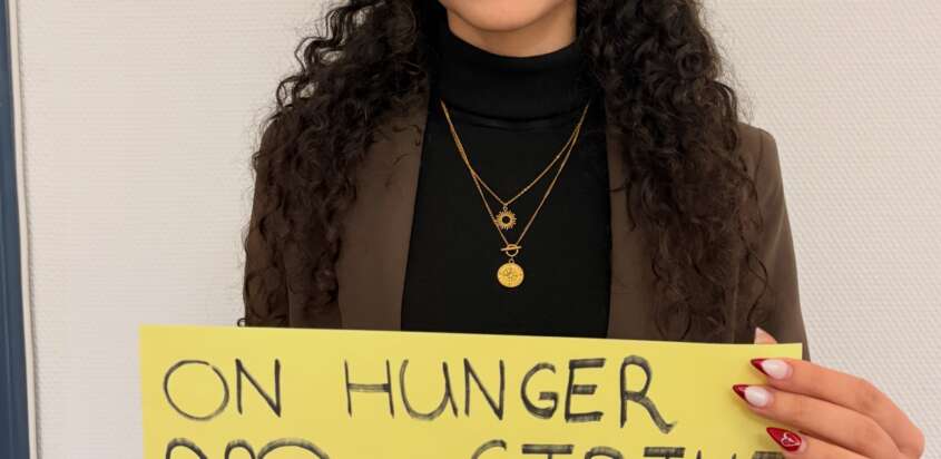 Solidaritätsaktion für die Kampagne „Dienstage gegen Hinrichtungen“: Person mit gelbem Schild gegen Hinrichtungen im Iran.