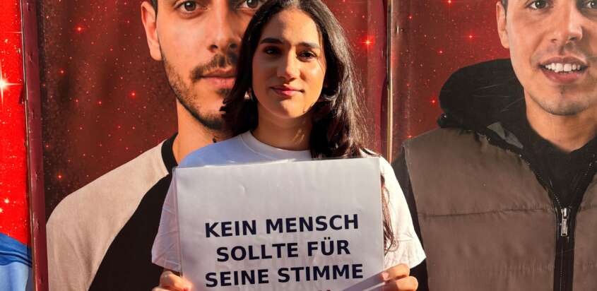 Teilnehmerin beim Solidaritätslauf in Köln mit dem Schild „Kein Mensch sollte für seine Stimme sterben“.